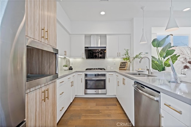 kitchen featuring light countertops, stainless steel appliances, backsplash, a sink, and wood finished floors