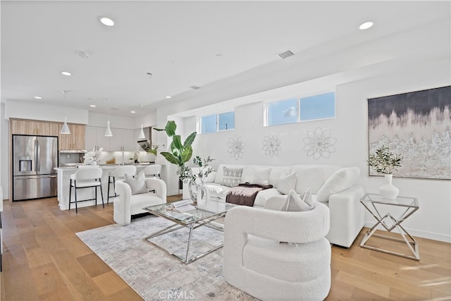 living area with baseboards, visible vents, light wood-style flooring, and recessed lighting