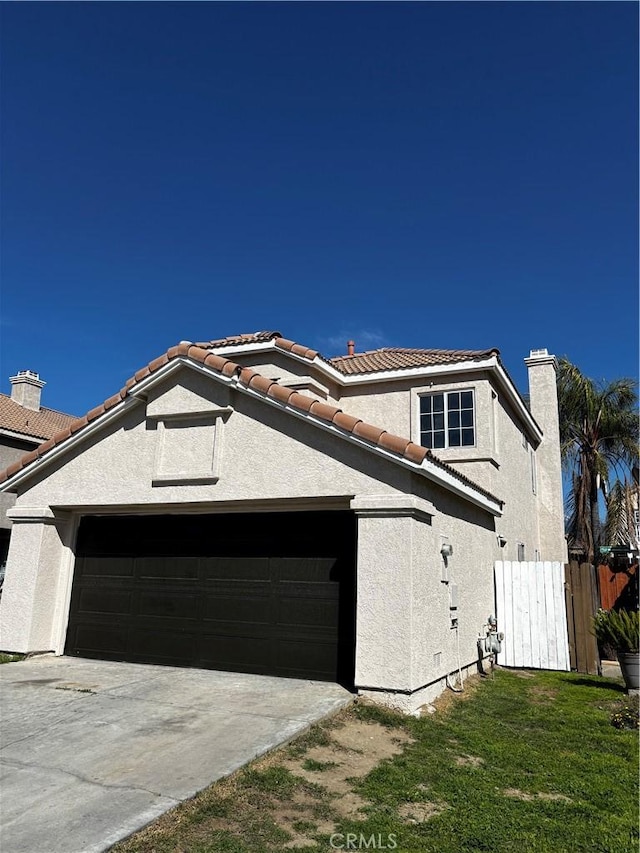 view of front of property featuring a garage, stucco siding, fence, and a chimney