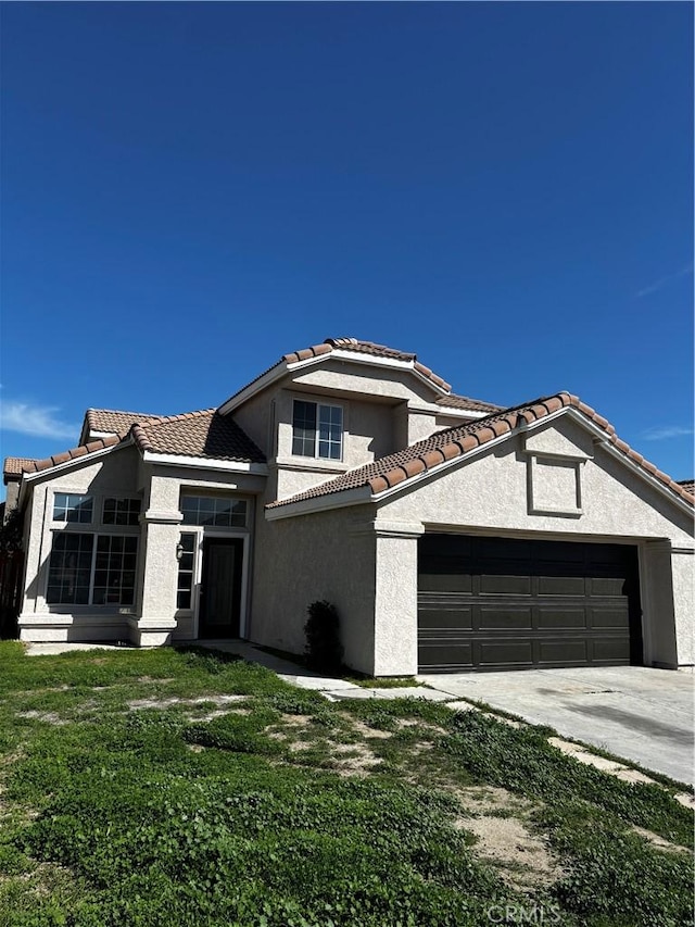 view of front of property with a tile roof, stucco siding, an attached garage, driveway, and a front yard