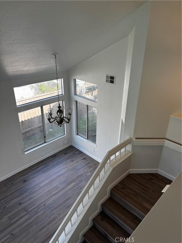 stairs with baseboards, visible vents, a chandelier, and wood finished floors