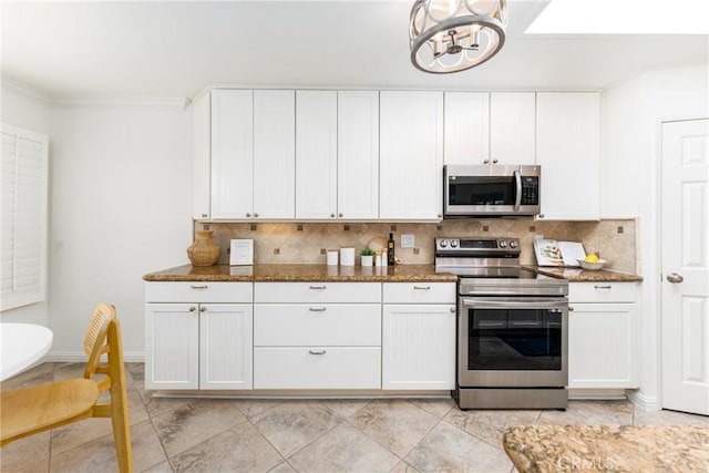 kitchen with appliances with stainless steel finishes, a chandelier, dark stone counters, white cabinetry, and tasteful backsplash