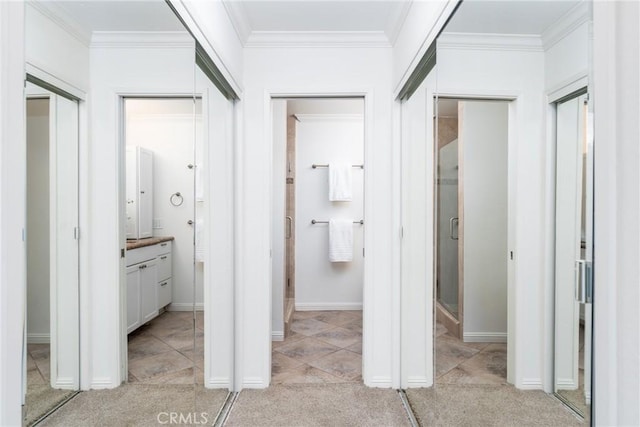 corridor featuring baseboards, ornamental molding, and light carpet