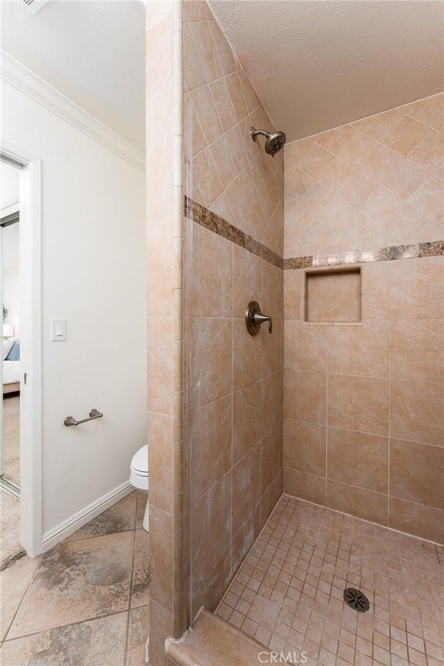 bathroom with crown molding, a tile shower, and toilet