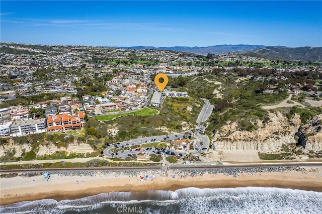 drone / aerial view with a water and mountain view and a view of the beach