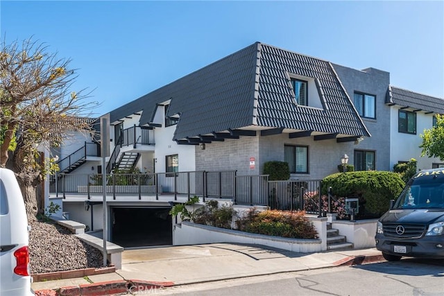 view of property featuring concrete driveway, stairway, and a garage