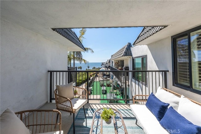 balcony with an outdoor living space and a water view