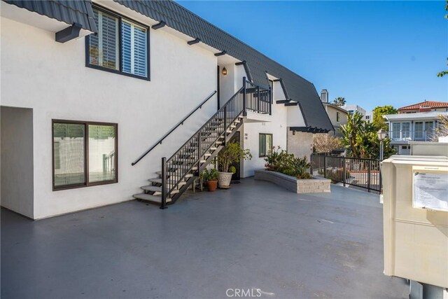 view of home's exterior with a patio, stucco siding, stairway, and fence