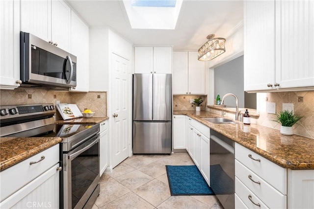 kitchen with a sink, appliances with stainless steel finishes, backsplash, and white cabinetry