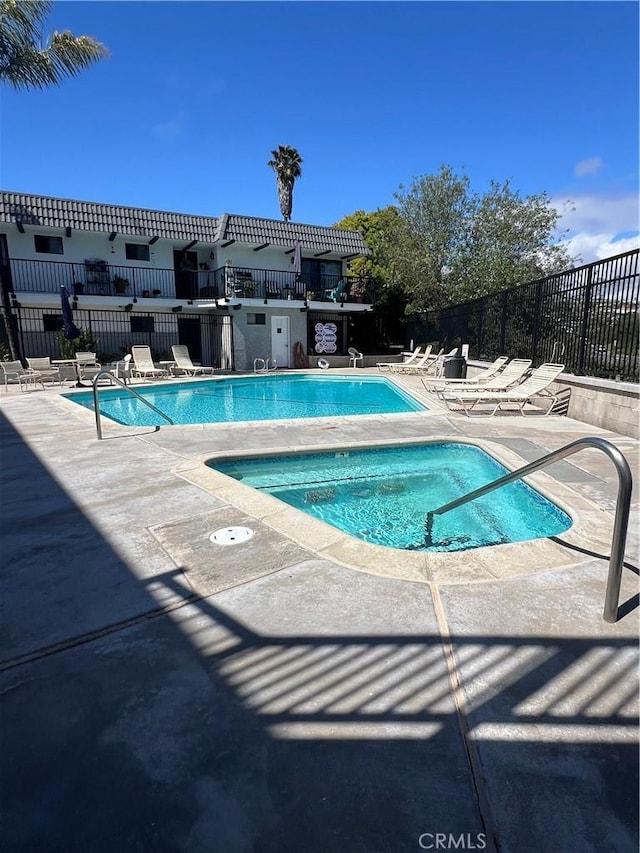 community pool featuring a patio, a community hot tub, and fence