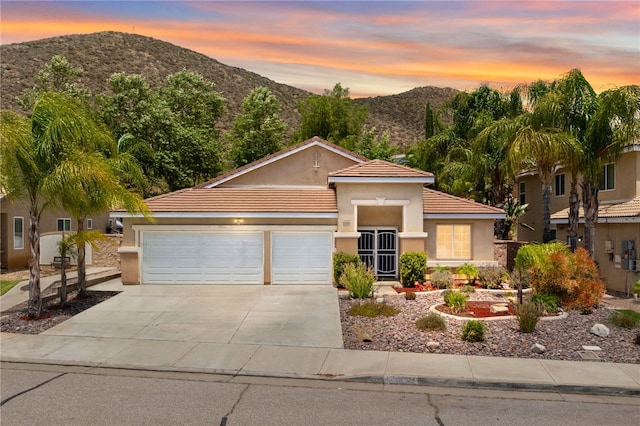 24898 Sunset Vista Ave, Menifee, CA 92584 - view of front of home with a mountain view, driveway, a garage, stucco siding, and a tiled roof