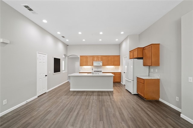 24898 Sunset Vista Ave, Menifee, CA 92584 - kitchen featuring white appliances, baseboards, light countertops, a center island with sink, and dark wood-style flooring