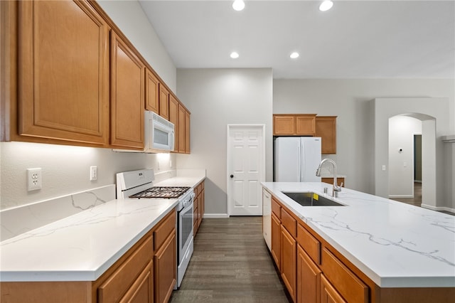 24898 Sunset Vista Ave, Menifee, CA 92584 - kitchen with white appliances, a sink, arched walkways, dark wood finished floors, and brown cabinets