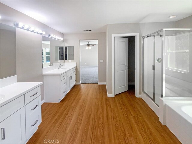 full bath with a ceiling fan, a sink, wood finished floors, and a shower stall