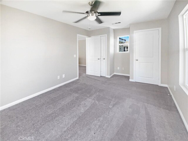 unfurnished bedroom with a closet, carpet floors, a ceiling fan, baseboards, and visible vents