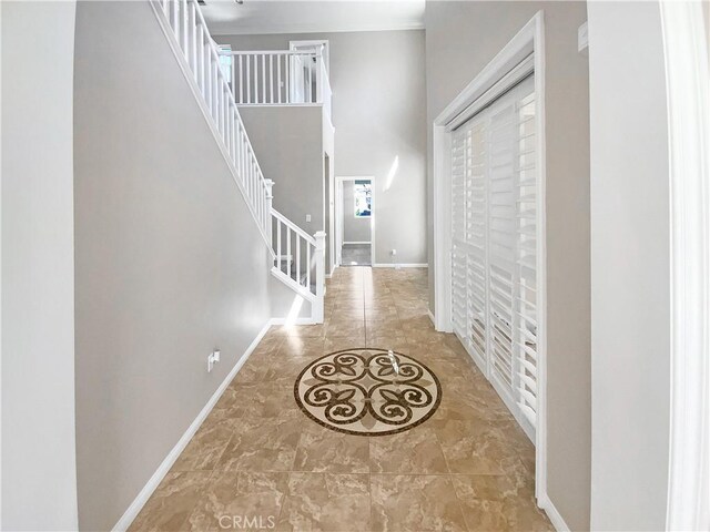 entrance foyer with a towering ceiling, baseboards, and stairway