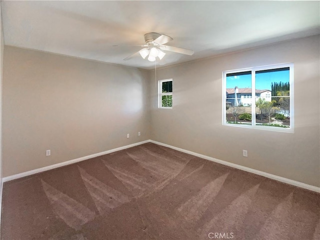 spare room featuring baseboards, dark colored carpet, and ceiling fan