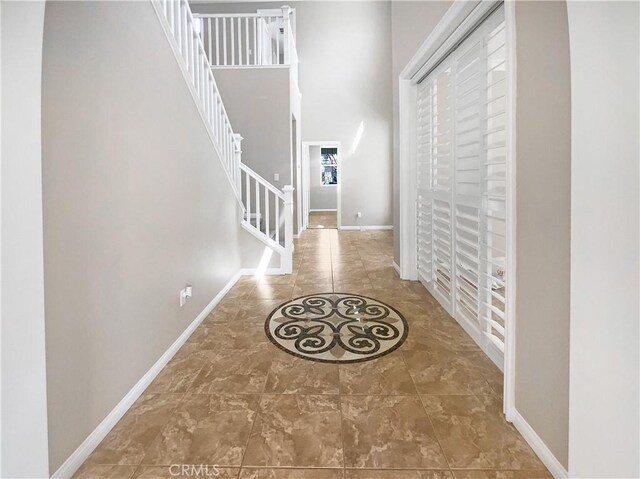 entryway featuring baseboards, stairs, and a high ceiling