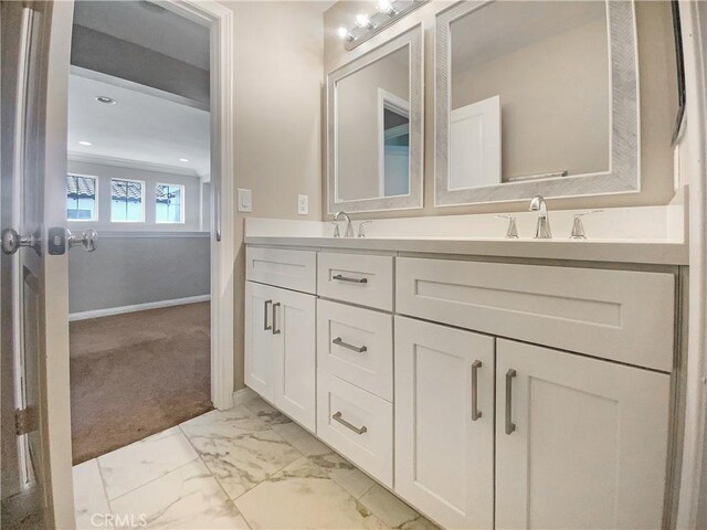 bathroom with marble finish floor, a sink, double vanity, and baseboards