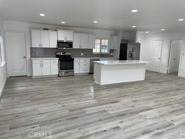 12472 Woodlawn Ave, Tustin, CA 92780 - kitchen with light countertops, light wood-style flooring, stainless steel appliances, and tasteful backsplash