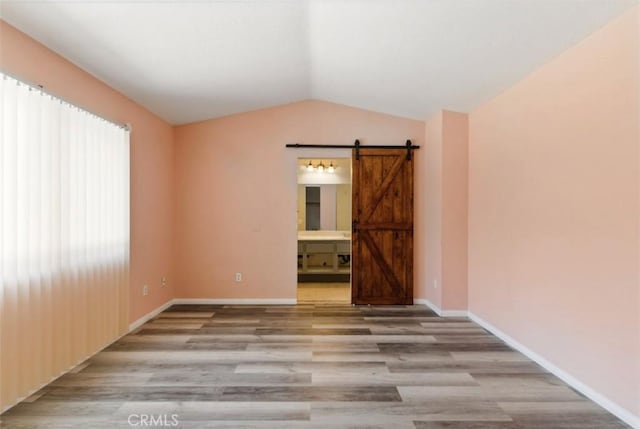 595 Casey Ct, Colton, CA 92324 - empty room featuring wood finished floors, a barn door, vaulted ceiling, and baseboards