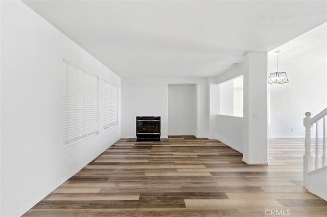 595 Casey Ct, Colton, CA 92324 - unfurnished living room with a fireplace, wood finished floors, a chandelier, stairs, and healthy amount of natural light
