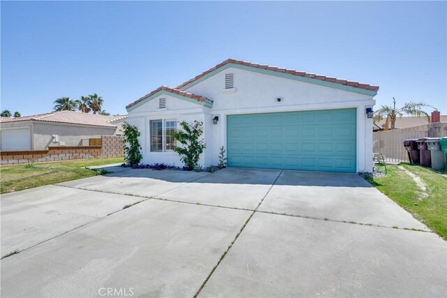 mediterranean / spanish home featuring stucco siding, an attached garage, fence, and concrete driveway