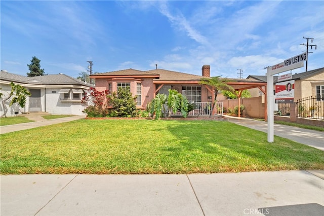 view of front of house with concrete driveway, a chimney, stucco siding, a front yard, and fence