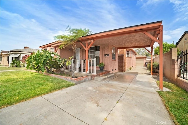 view of front of home featuring driveway, stucco siding, covered porch, fence, and a front lawn