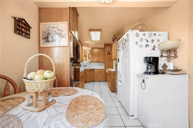kitchen featuring white fridge with ice dispenser, brown cabinetry, light countertops, oven, and light tile patterned flooring