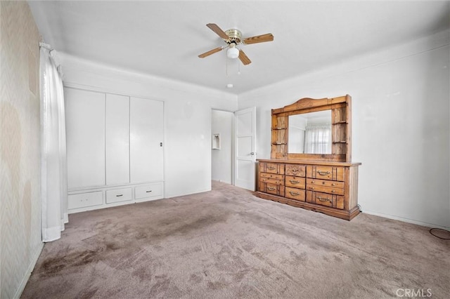 unfurnished bedroom with a ceiling fan, carpet flooring, wallpapered walls, and a closet