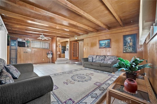 living area featuring beam ceiling, ceiling fan, tile patterned floors, wooden walls, and wood ceiling