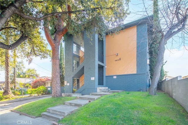 view of front of property featuring brick siding, fence, a front lawn, and entry steps