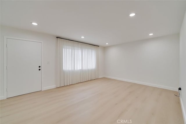 empty room featuring baseboards, light wood-type flooring, and recessed lighting