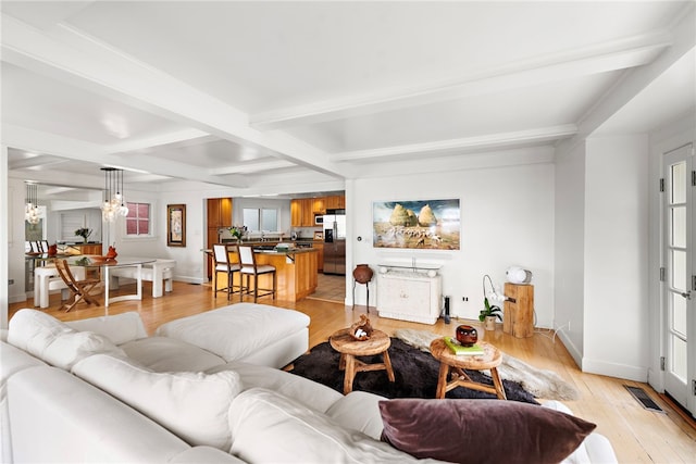 living area featuring visible vents, baseboards, beam ceiling, light wood-type flooring, and a notable chandelier