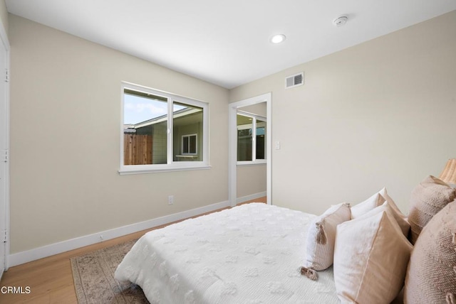 bedroom featuring wood finished floors, baseboards, visible vents, and recessed lighting