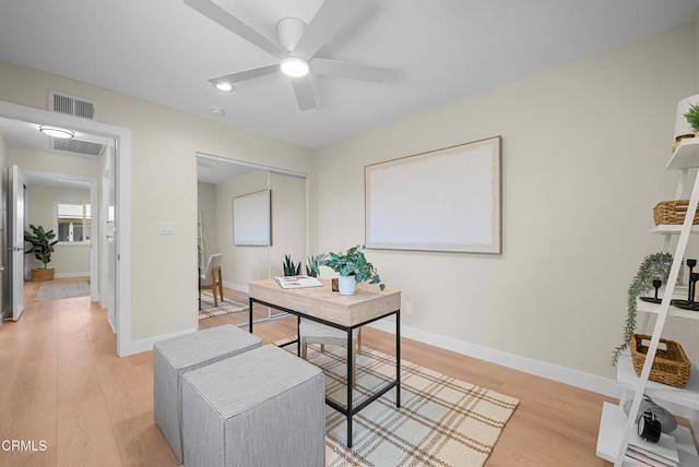 home office with light wood finished floors, visible vents, baseboards, and a ceiling fan
