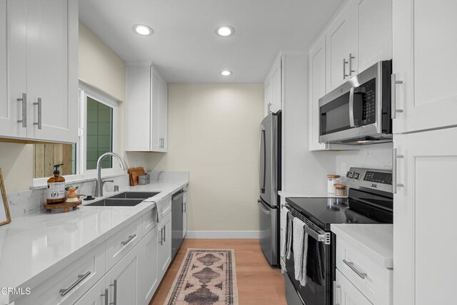 kitchen featuring light wood-style flooring, white cabinetry, recessed lighting, appliances with stainless steel finishes, and a sink