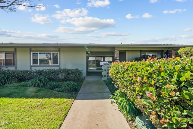 property entrance with stucco siding and a lawn