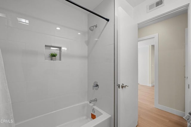 full bathroom with shower / bath combo with shower curtain, visible vents, baseboards, and wood finished floors