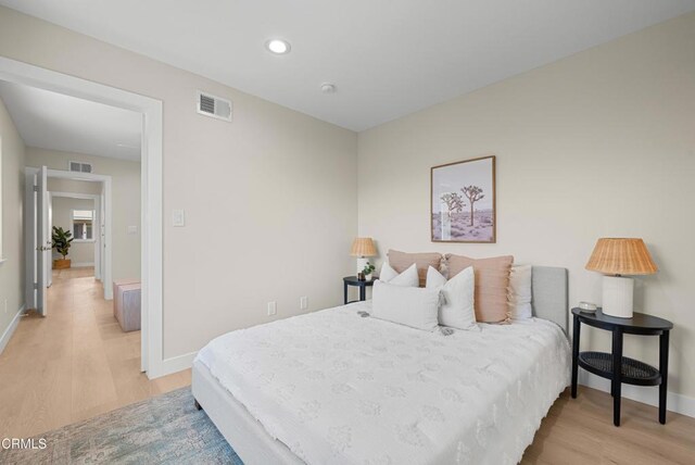 bedroom featuring visible vents, light wood-type flooring, and baseboards