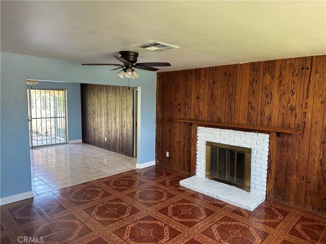878 E Holly St, Rialto, CA 92376 - unfurnished living room featuring wooden walls, a ceiling fan, a fireplace, and a textured ceiling