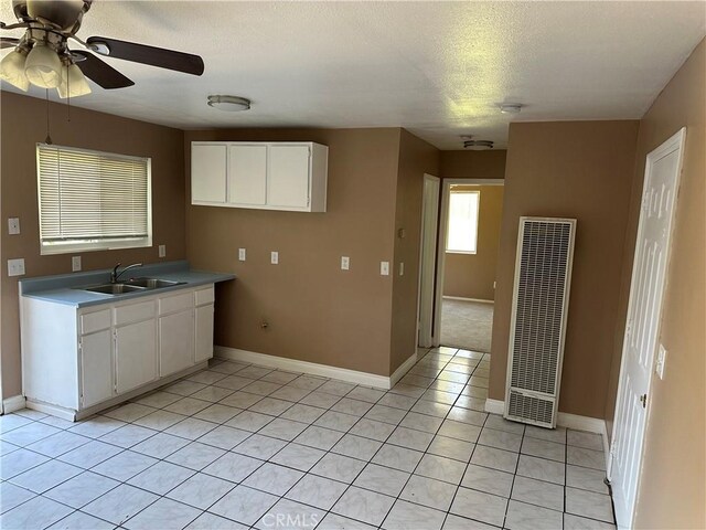 878 E Holly St, Rialto, CA 92376 - kitchen with a heating unit, a ceiling fan, light tile patterned floors, white cabinets, and light countertops