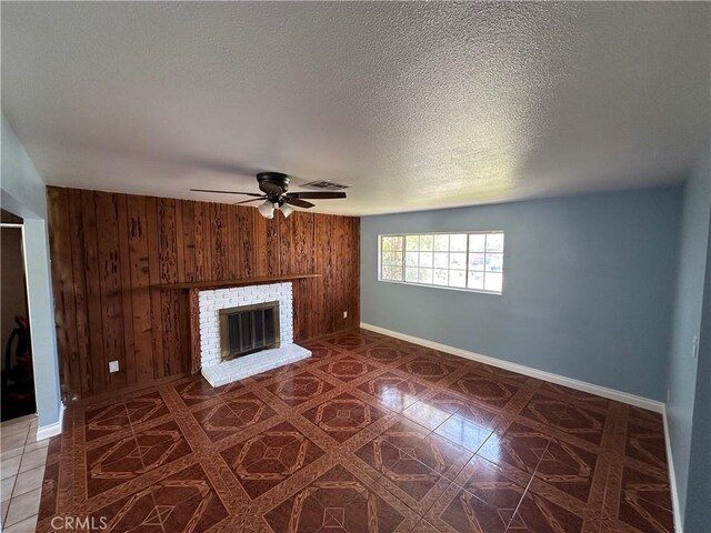 878 E Holly St, Rialto, CA 92376 - unfurnished living room with wood walls, ceiling fan, a brick fireplace, and a textured ceiling