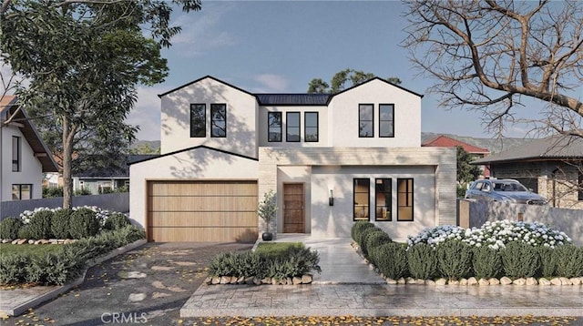 view of front facade with stucco siding, fence, a garage, and aphalt driveway