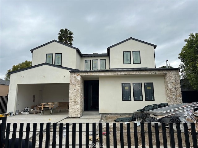 view of front of house with a patio, a garage, fence, and stucco siding