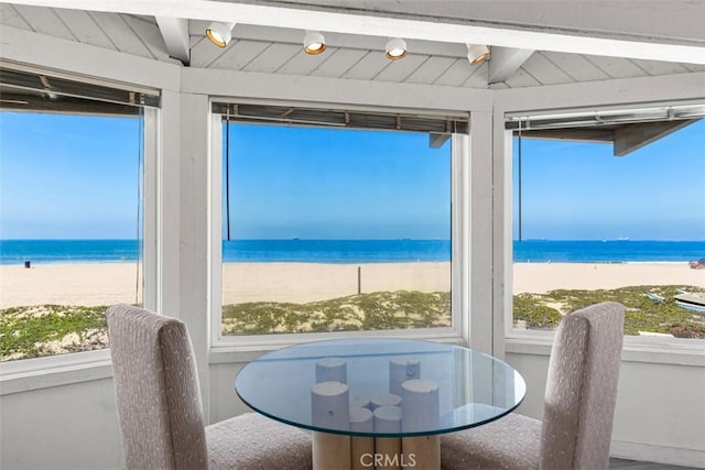dining area with plenty of natural light, a water view, and a beach view