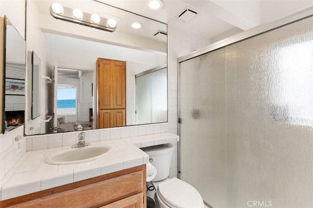 full bathroom featuring visible vents, a stall shower, toilet, and vanity
