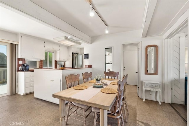 dining room with beam ceiling and light floors