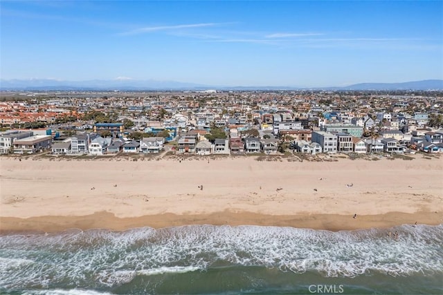 drone / aerial view with a water and mountain view, a view of the beach, and a residential view